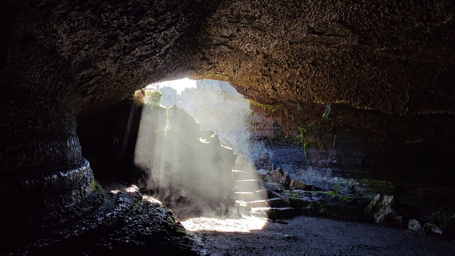 The Valentine Cave entrance — a staircase descending into cool shadow among volcanic rubble.