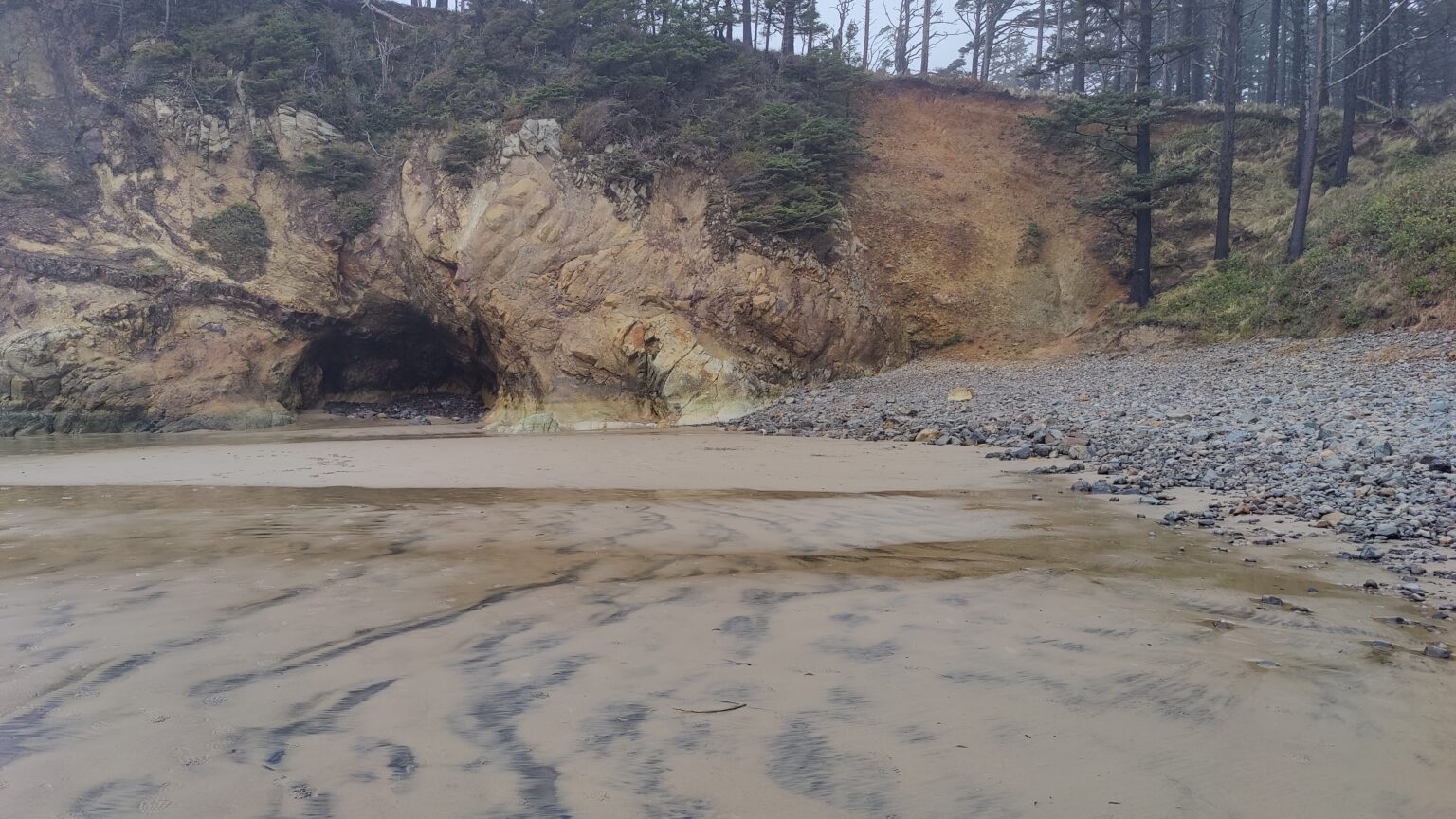 Hug Point sea arch on the Oregon coast at low tide, water sliding through the stone.